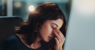 junge Frau am Arbeitsplatz. Stützt ihren Kopf auf. Scheinbar Kopfschmerzen. Vielleicht durch viele negative Gedanken. Aber wie können diese gestoppt werden. Michael Lahme Coaching Düsseldorf hat dazu einen Artikel verfasst.