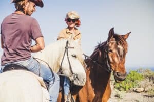 Work Life Balance. Ein Paar findet ihren Ausgleich beim Reiten. Fröhlicher Ausflug in der sonnigen Natur trotz Herausforderungen in Job und Haushalt.