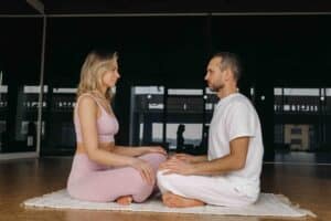 Ein Paar sitzt sich während einer Yoga-Übung gegenüber und meditiert. Zeit für Gemeinsamkeiten.