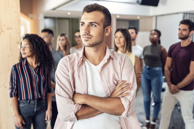 Mehrere Menschen stehen beieinander. Wertende und skeptische Blicken gehen in eine Richtung. Wertungen in der Beziehung stören die Emotionale Bindung.