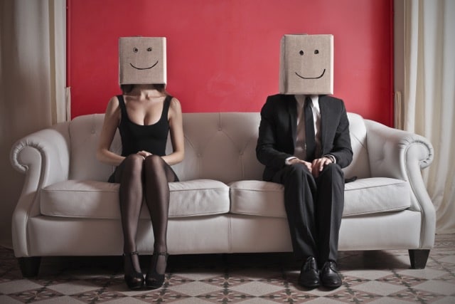 Paar sitzt mit Abstand auf der Couch – Symbol für emotionale Unerreichbarkeit in der Beziehung